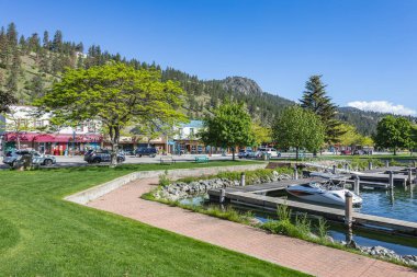 Yürüme yolu ve gölün yanındaki yeşil çimenlik. Yaz güneşli bir günde Kanada Peachland 'da dükkanları ve restoranları olan ana cadde. Okanagan Gölü 'nün yanındaki halka açık yeşil park. Seyahat fotoğrafı, yaz tatili konsepti.
