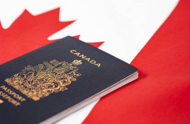 Close up photo of a passport of Canada on the top of an Canadian flag. Copy space for text, nobody. Canadian passport on a red maple leaf Canadian Flag background. Travel visa and citizenship concept