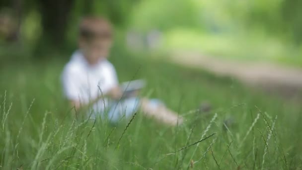 Niño con tablet PC y auriculares al aire libre . — Vídeos de Stock