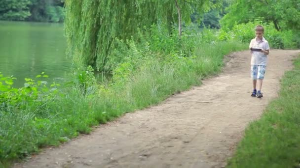 Jeune garçon avec tablette PC et casque à l'extérieur . — Video