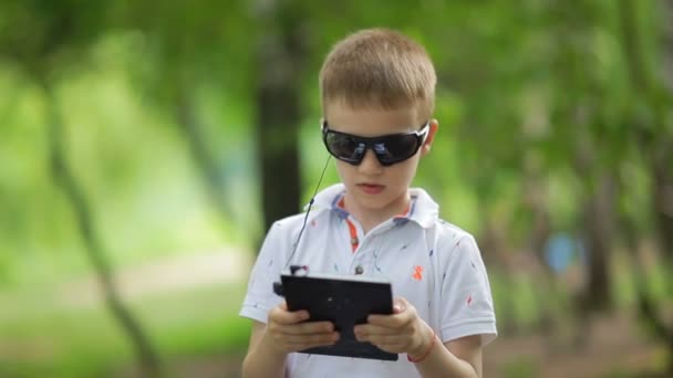 Jeune garçon avec tablette PC et casque à l'extérieur . — Video