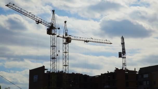 Arbeitskran auf dem Bau des Hauses. Baustelle mit Kränen am Himmel. — Stockvideo