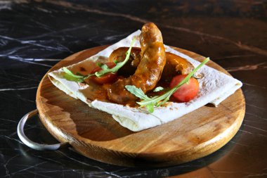 Sausages grilled pork with smoked cheese, Serving fresh cherry tomatoes and arugula on a pita. Grilled sausages with tomatoes and pita on a wooden plank. Grilled sausages with beer - Stock Image