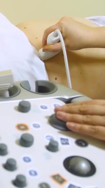 Modern ultrason cihazı. İç organların ultrason muayenesi. Karın boşluğunda ultrason taraması yapılan bir kadın. Ultrason inceleme aygıtı - dikey video