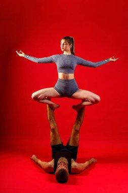 Kırmızı zemin üzerinde akro-yoga dersleri
