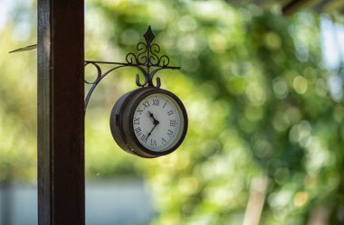 Güneşli bir Eylül gününde arka planda bulanık bir görüntü olan direğin üzerindeki saat.