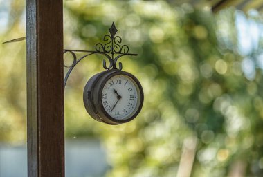 Güneşli bir Eylül gününde arka planda bulanık bir görüntü olan direğin üzerindeki saat.