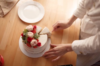 Kadın eli böğürtlen ve çiçeklerle pasta keser