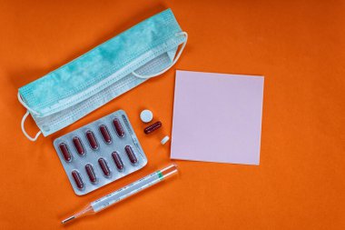 Yüzünde termometre, ilaç, bandaj ve bir parça kağıt.