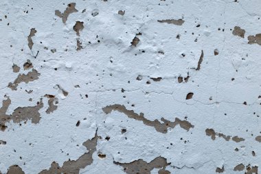 Bulutlu bir sonbahar gününde çekilen, parçalanmış beyaz boyalı, sıva tuğla bir duvarın parçası.