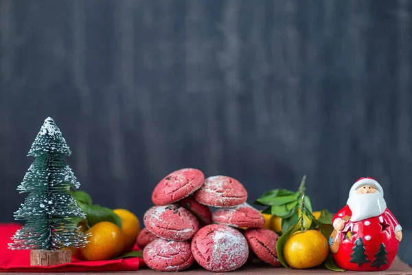 Oyuncak Noel ağacı ve Noel Baba, mandalina ve arka planda pembe kurabiyeler.