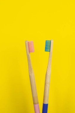 Sarı arka planda iki pembe ve mavi diş fırçası.