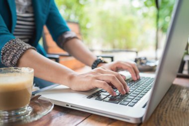 Bir kafede dizüstü bilgisayar üzerinde çalışan erkek.