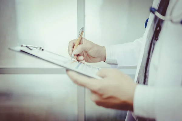 Close-up Of Male Doctor Filling The Medical Form