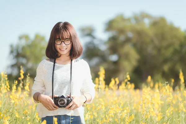 Young woman with camera in the Sunhemp garden Stock Photo