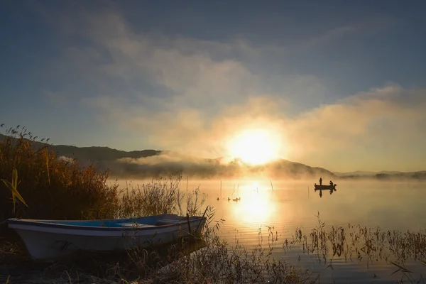 Soluppgång på sjön Kawaguchiko, människor som fiskar på en båt, silhoue — Stockfoto