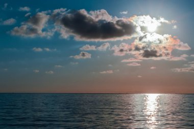 Bulutlu gökyüzü ile sakin denizde güzel bir gün batımı