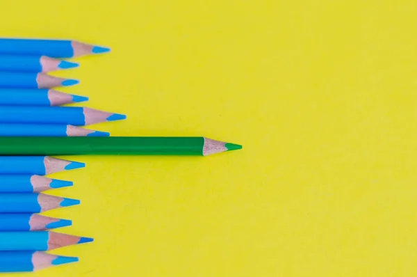 Sharpened blue pencils and one green pencil on a yellow background.School concept