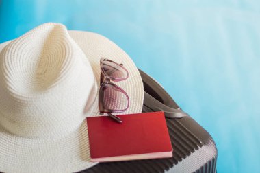 Güneş gözlüklü şık bavul ve mavi arka planda pasaport, üst manzara.