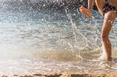 Mutlu çocuk sahilde su sıçratmaca oynuyor. Yaşam tarzı.