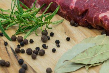 Biftek, ahşap bir tahtada taze et manzarası biberiye, karabiber, tuvalet yaprağı..