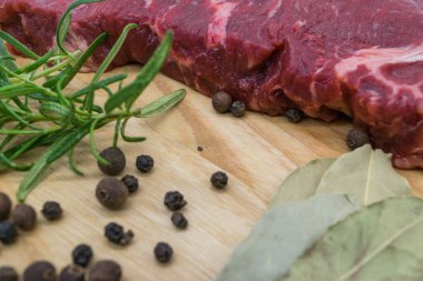 Biftek, ahşap bir tahtada taze et manzarası biberiye, karabiber, tuvalet yaprağı..