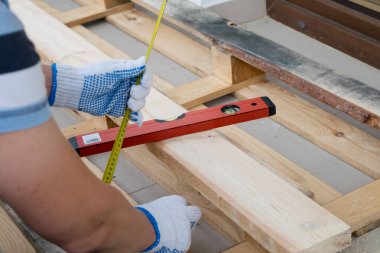 Beyaz eldivenli bir adam mezura ile çam ağacını ölçer.