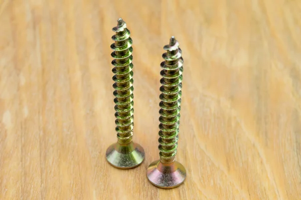 Metal screws for wood. Close-up view of metal wood screws on a wooden background.