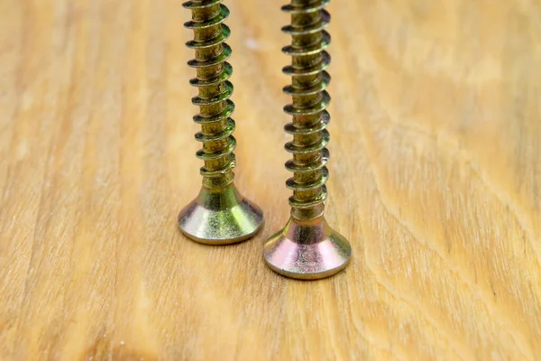 Metal screws for wood. Close-up view of metal wood screws on a wooden background.