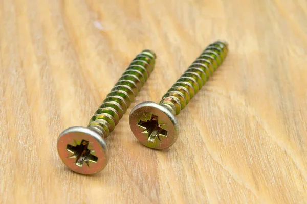 Metal screws for wood. Close-up view of metal wood screws on a wooden background.