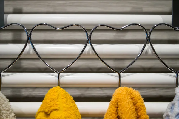 View of a heart-shaped towel rail with hanging colorful towels