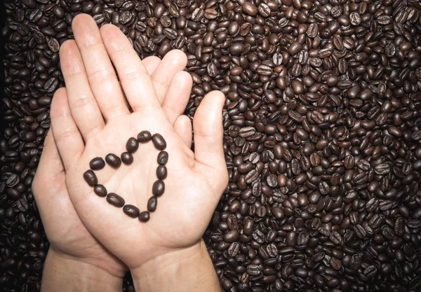 Coffee beans heart symbol on top of the hand — Stock Photo, Image