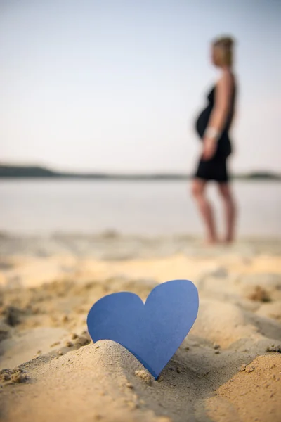 Hjerte og en gravid pige på stranden - Stock-foto