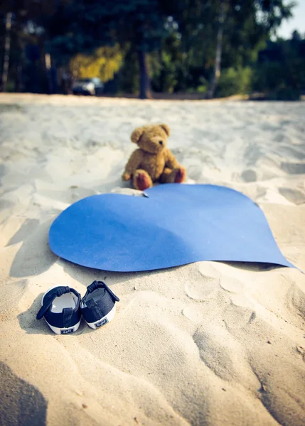 Крихітні туфлі, плюшевий ведмідь і серце — стокове фото