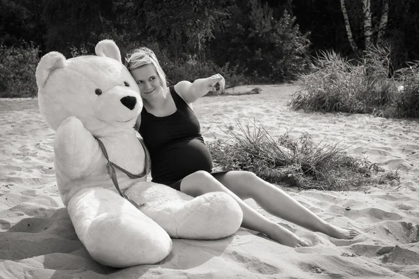 Mooie zwangere vrouw met een teddybeer — Stockfoto