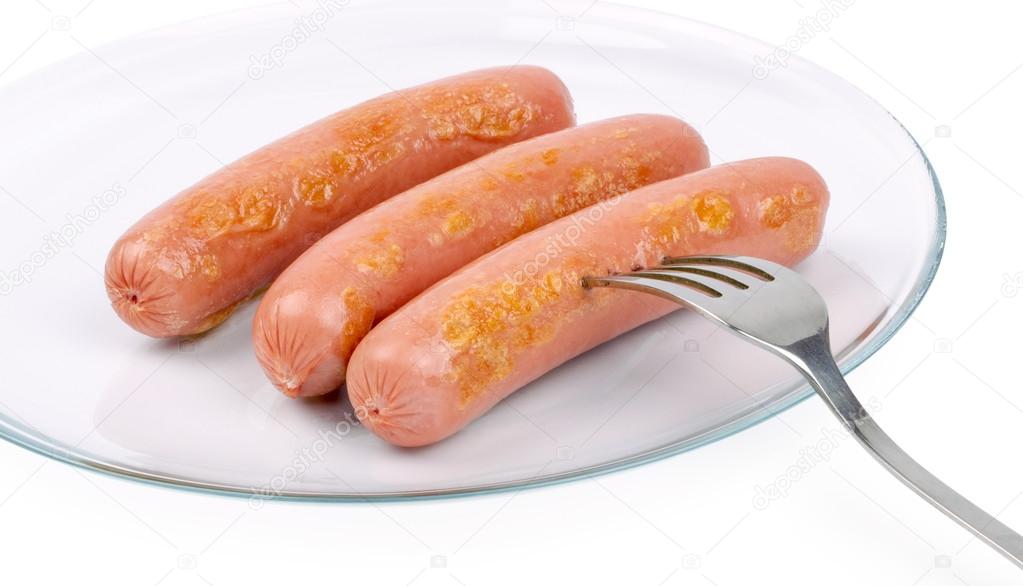 Three delicious frankfurters on a white plate