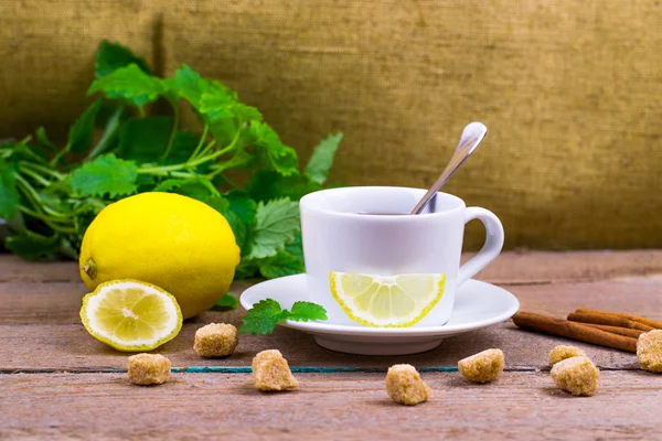 Tea with a lemon, a lime, cinnamon, a melissa and cane sugar — Stock Photo, Image