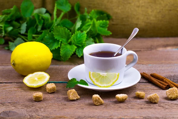 Tea with a lemon, a lime, cinnamon, a melissa and cane sugar — Stock Photo, Image