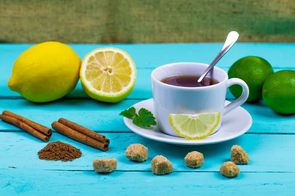 Tea with a lemon, a lime, cinnamon, a melissa and cane sugar — Stock Photo, Image