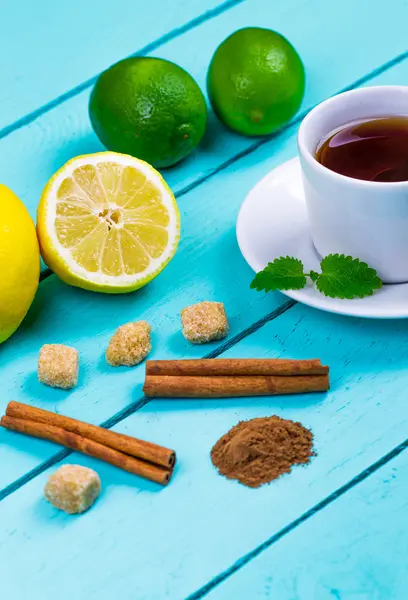 Tea with a lemon, a lime, cinnamon, a melissa and cane sugar — Stock Photo, Image