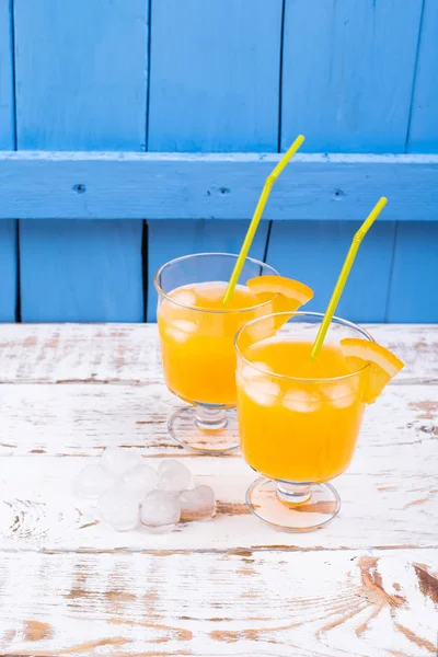 Suco de laranja em vidro com gelo em uma mesa de madeira — Fotografia de Stock