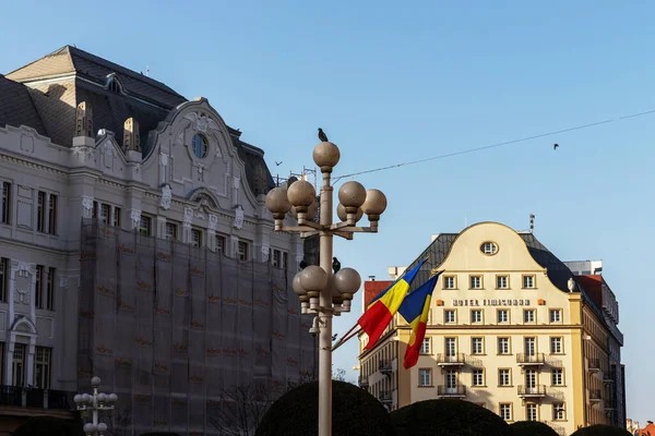 Timisoara, Romanya, 26 Şubat 2020; Romanya 'nın bayrakları üzerine bir kaç güvercin yerleştirilmiş ve arkasında Timisoara Oteli' nin resmi var.