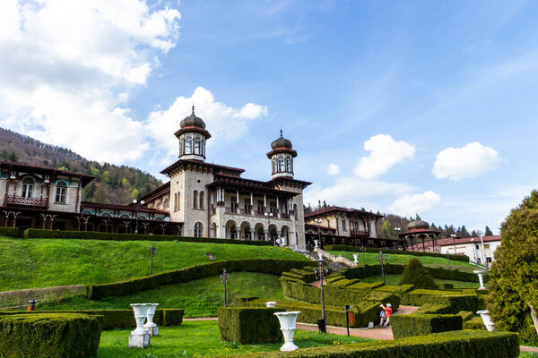 Slanic Moldova, Romania-May 02, 2021: The casino from Slanic Moldova, Bacau, historical monument, surrounded by a beautifully arranged green garden, from the park in the center of the city; springtime, blue sky, easter day