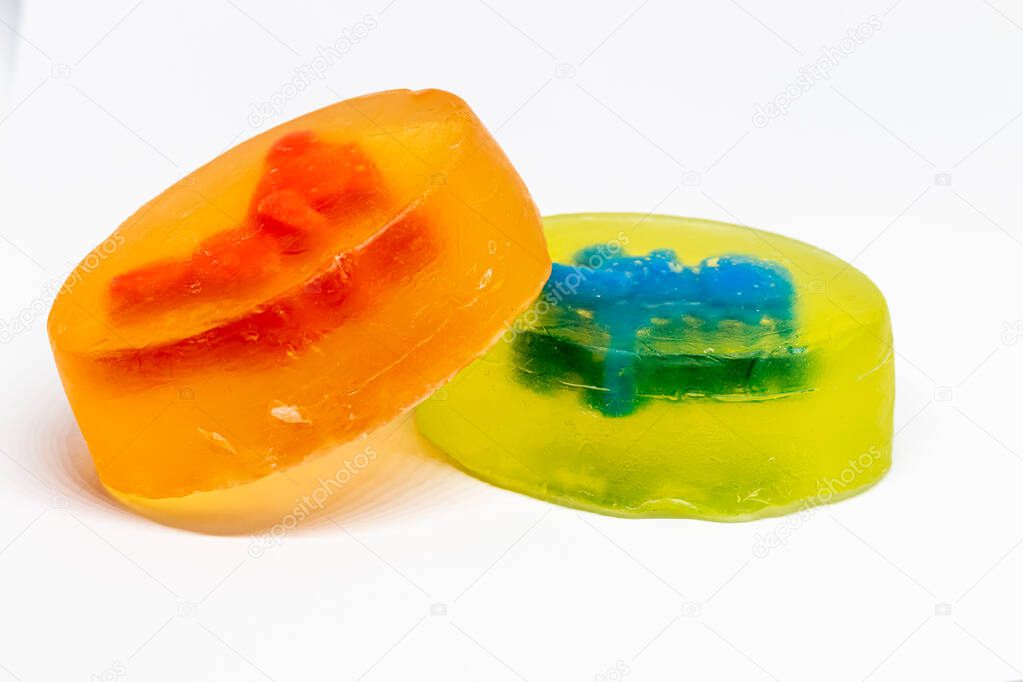 Homemade glycerin soaps for children with toys, dinosaur and rabbit inside, photographed close up on a white background. Studio photography