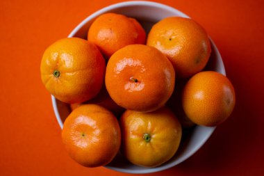 Naranjas duls on bowl blanco y fondo naranjo