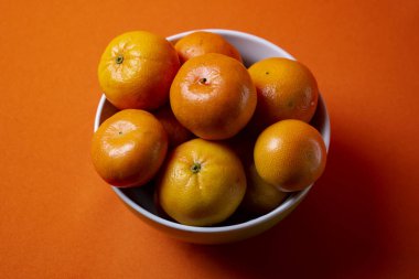 Naranjas duls on bowl blanco y fondo naranjo