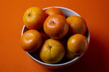 Naranjas duls on bowl blanco y fondo naranjo