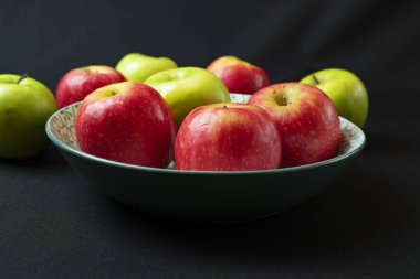 Manzanas en plato celeste en fondo negro