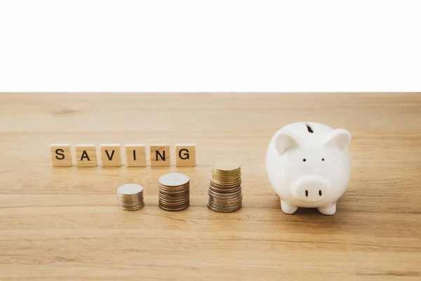 Saving cash coin concept investment by putting money to piggy bank. Management growth funding budget for wealth. Wooden background with saving word.