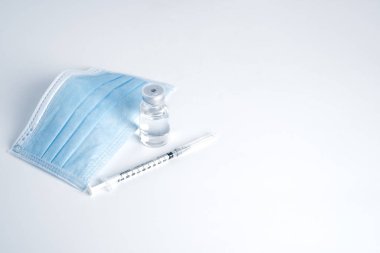 Empty bottle of vaccine with syringe and mask for hygiene injection. Pharmaceutical equipment protective infection of pandemic covid-19 virus, flu, disease. Isolated on white background, copy space.